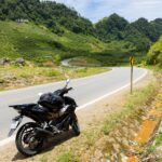 Motocykl na krętej górskiej drodze wśród zielonych wzgórz