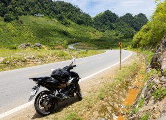 Motocykl na krętej górskiej drodze wśród zielonych wzgórz