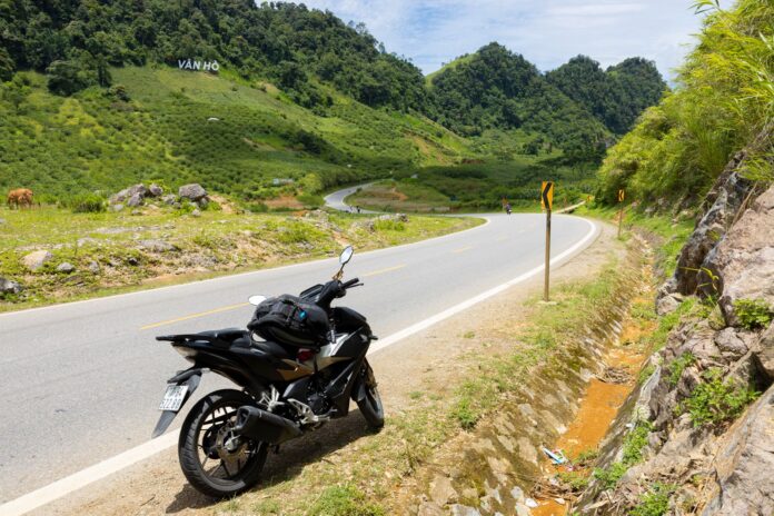 Motocykl na krętej górskiej drodze wśród zielonych wzgórz
