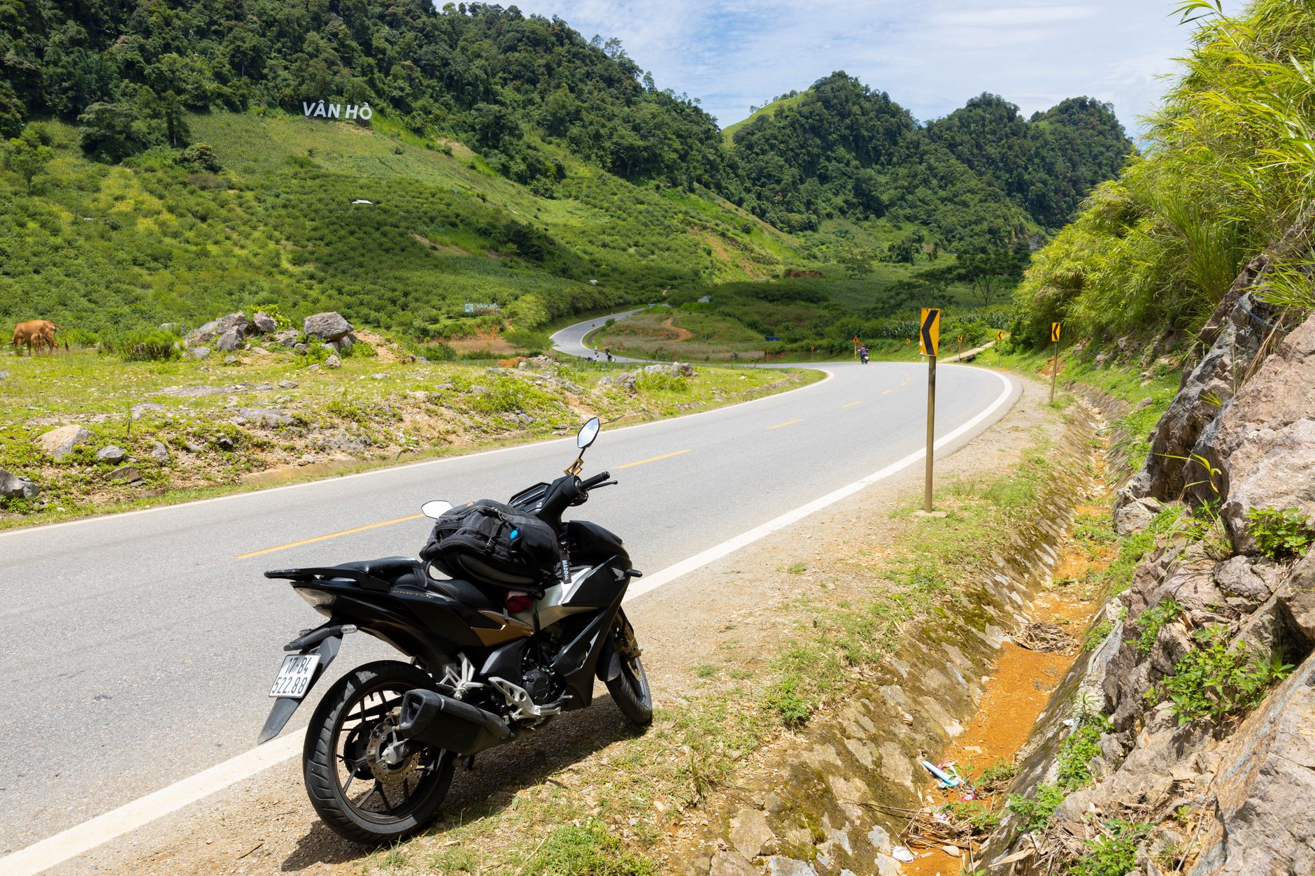 Motocykl na krętej górskiej drodze wśród zielonych wzgórz