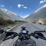 Motocyklista jedzie krętą górską drogą w słoneczny, bezchmurny dzień