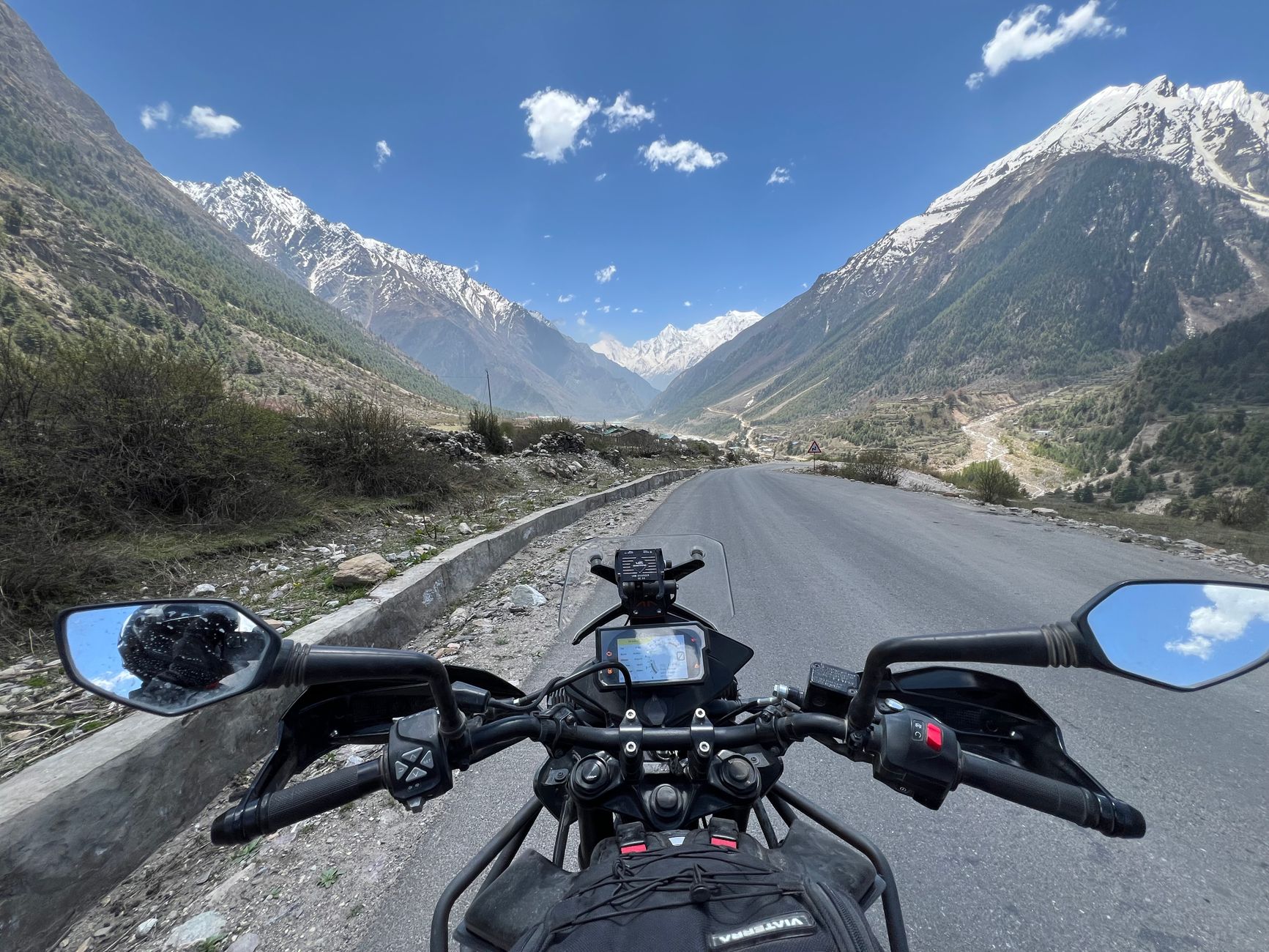 Motocykl na krętej górskiej drodze wśród zielonych wzgórz