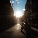Motocyklista w alei miejskiej o zachodzie słońca, w mrocznej sylwetce