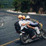 Trzech motocyklistów w kaskach jedzie krętą górską drogą