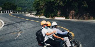 Trzech motocyklistów w kaskach jedzie krętą górską drogą