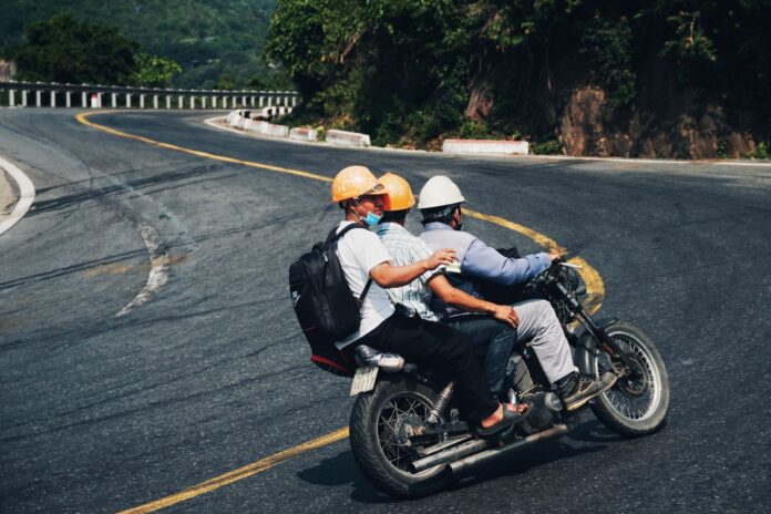 Trzech motocyklistów w kaskach jedzie krętą górską drogą Trzech motocyklistów w kaskach jedzie krętą górską drogą