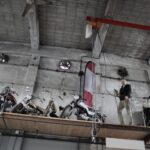 Brodaty mechanik w garażu przy motocyklach na podnośniku z pilotem