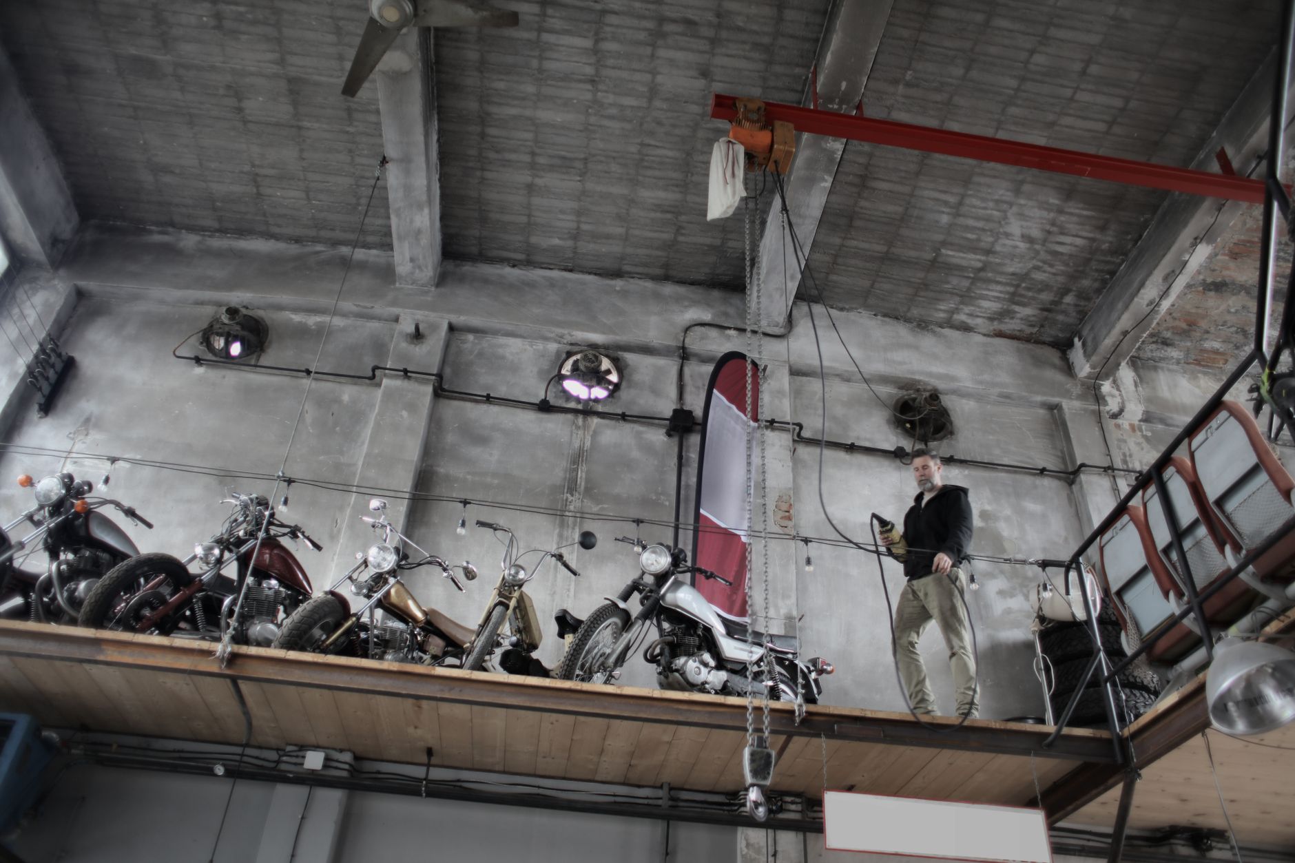 Brodaty mechanik w garażu przy motocyklach na podnośniku z pilotem