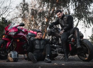 Motocyklowi bohaterowie anime i mangi, które musisz znać Dwóch motocyklistów w kombinezonach pozuje przy motocyklach na zewnątrz