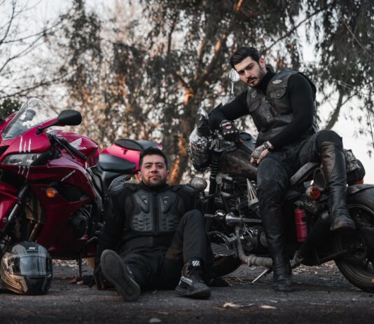 Motocyklowi bohaterowie anime i mangi, które musisz znać Dwóch motocyklistów w kombinezonach pozuje przy motocyklach na zewnątrz