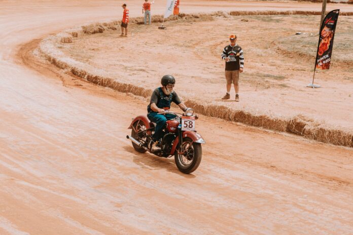 Klasyczny motocyklista pędzi po torze ziemnym podczas wyścigu Klasyczny motocyklista pędzi po torze ziemnym podczas wyścigu