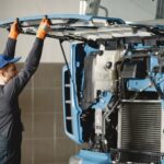 Mechanik w hali sprawdza silnik używanej ciężarówki z importu