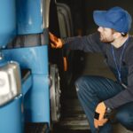 Mechanik w warsztacie sprawdza koło niebieskiej ciężarówki