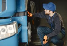 Jak bezpiecznie kupić używaną ciężarówkę z importu: praktyczny poradnik dla firm transportowych Mechanik w warsztacie sprawdza koło niebieskiej ciężarówki
