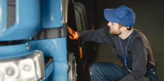 Mechanik w warsztacie sprawdza koło niebieskiej ciężarówki
