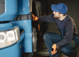 Jak bezpiecznie kupić używaną ciężarówkę z importu: praktyczny poradnik dla firm transportowych Mechanik w warsztacie sprawdza koło niebieskiej ciężarówki