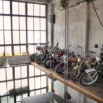 Rząd retro motocykli na podestach w garażu przy dużych oknach