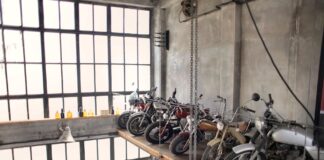 Rząd retro motocykli na podestach w garażu przy dużych oknach