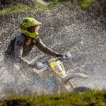 Zawodnik trial na motocyklu przejeżdża z chlapiącą wodą po trasie