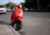 Czerwony skuter Vespa zaparkowany przy miejskiej ulicy