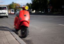 Dlaczego Vespa stała się symbolem wolności, stylu i miejskiej mobilności Czerwony skuter Vespa zaparkowany przy miejskiej ulicy