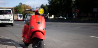 Czerwony skuter Vespa zaparkowany przy miejskiej ulicy