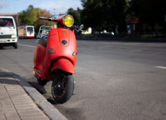 Czerwony skuter Vespa zaparkowany przy miejskiej ulicy