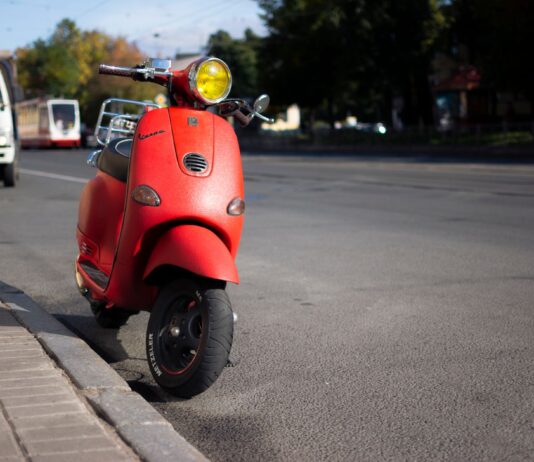 Dlaczego Vespa stała się symbolem wolności, stylu i miejskiej mobilności Czerwony skuter Vespa zaparkowany przy miejskiej ulicy