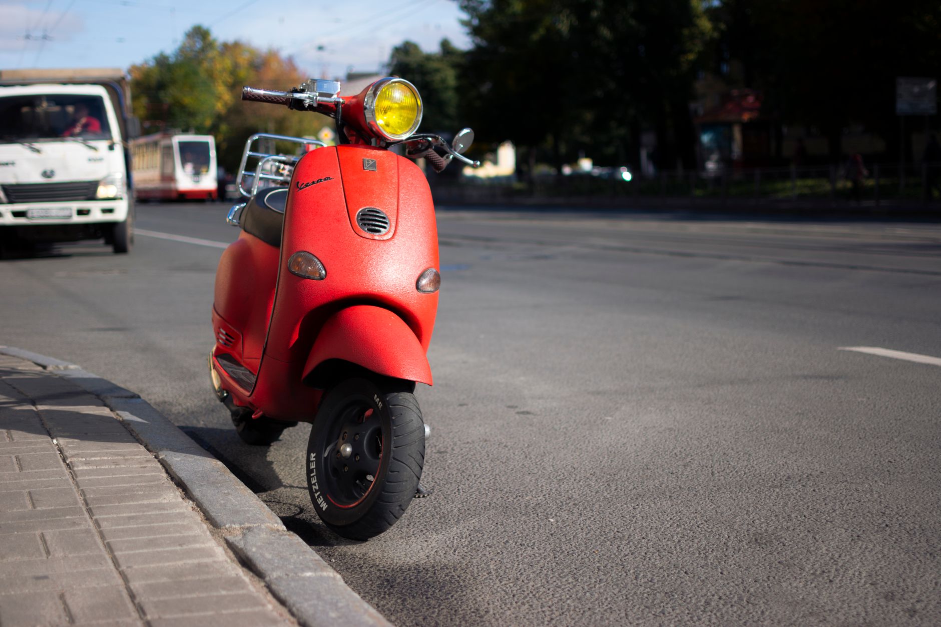 Czerwony skuter Vespa zaparkowany przy miejskiej ulicy