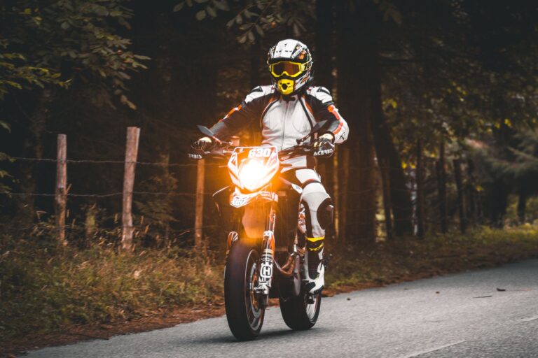 Motocyklista w pełnym stroju jedzie wiejską drogą