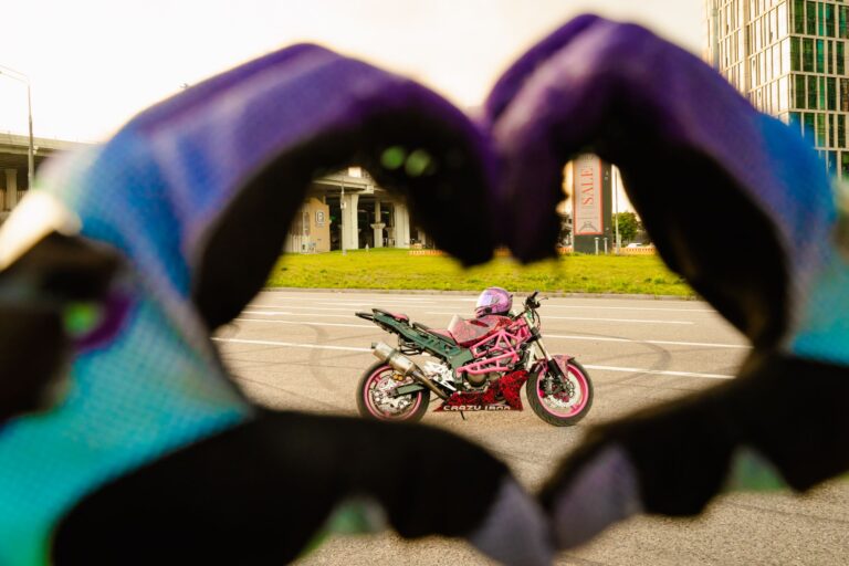 Różowy motocykl w kadrze dłoni ułożonych w